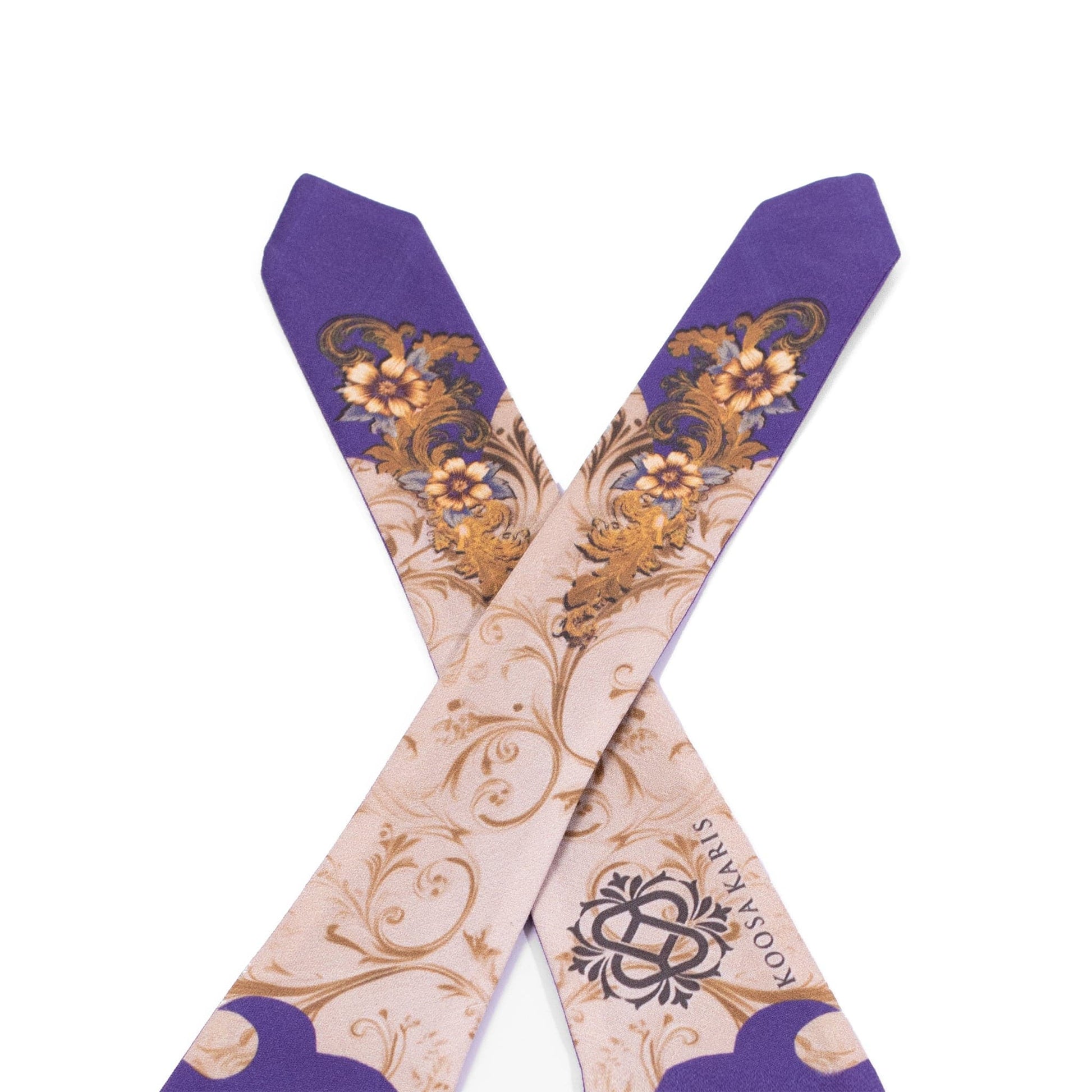 The tie ends of a beige dog bandana with a purple and gold paisley pattern 