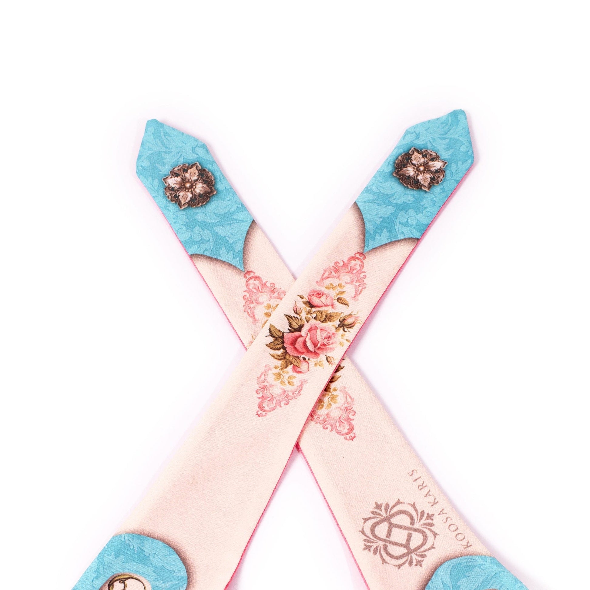 The tie ends of an ivory and turquoise colored dog bandana with pink roses