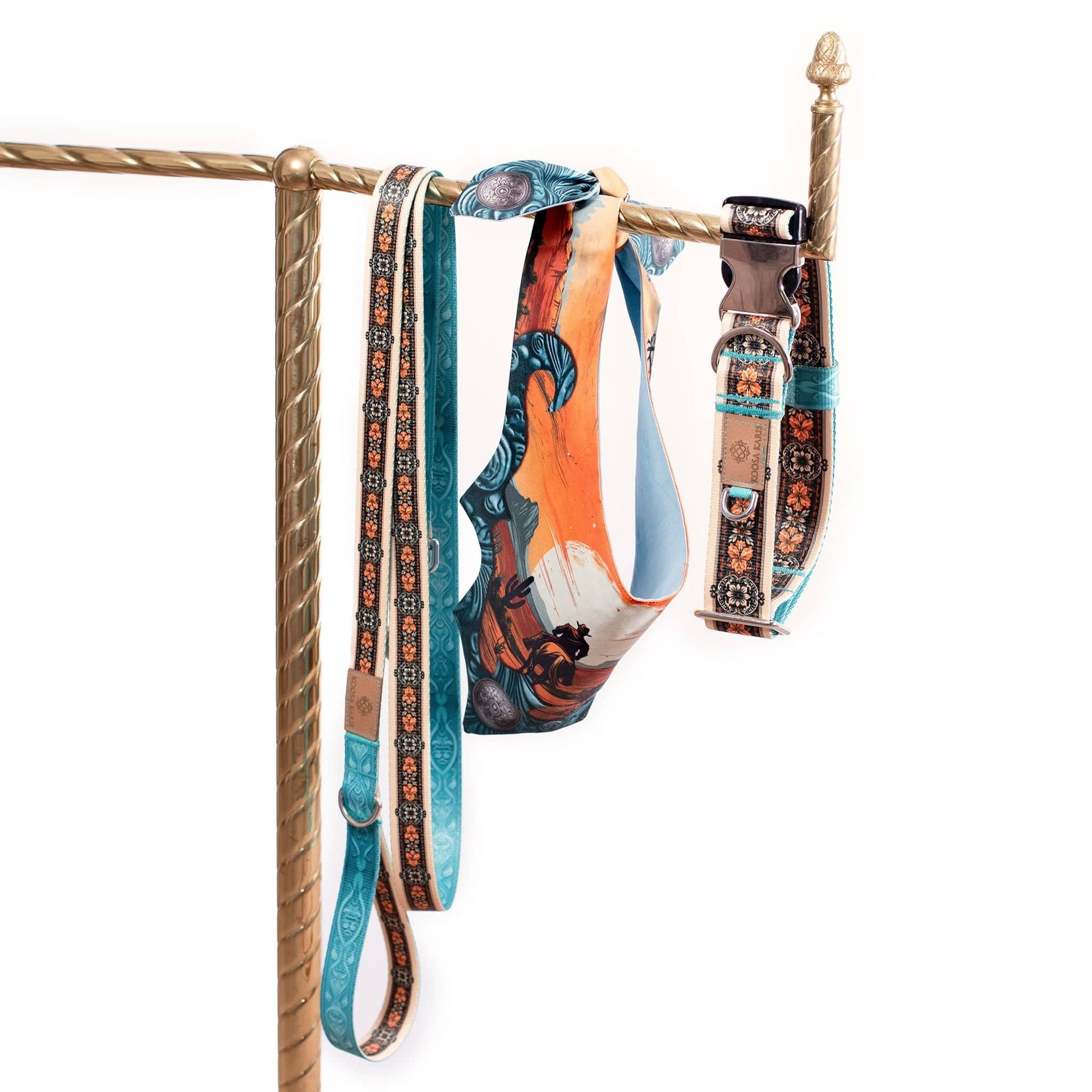 Ivory and turquoise colored dog collar and leash with a gold and black western floral pattern and a dog bandana that features a cowboy on horseback in a sunset