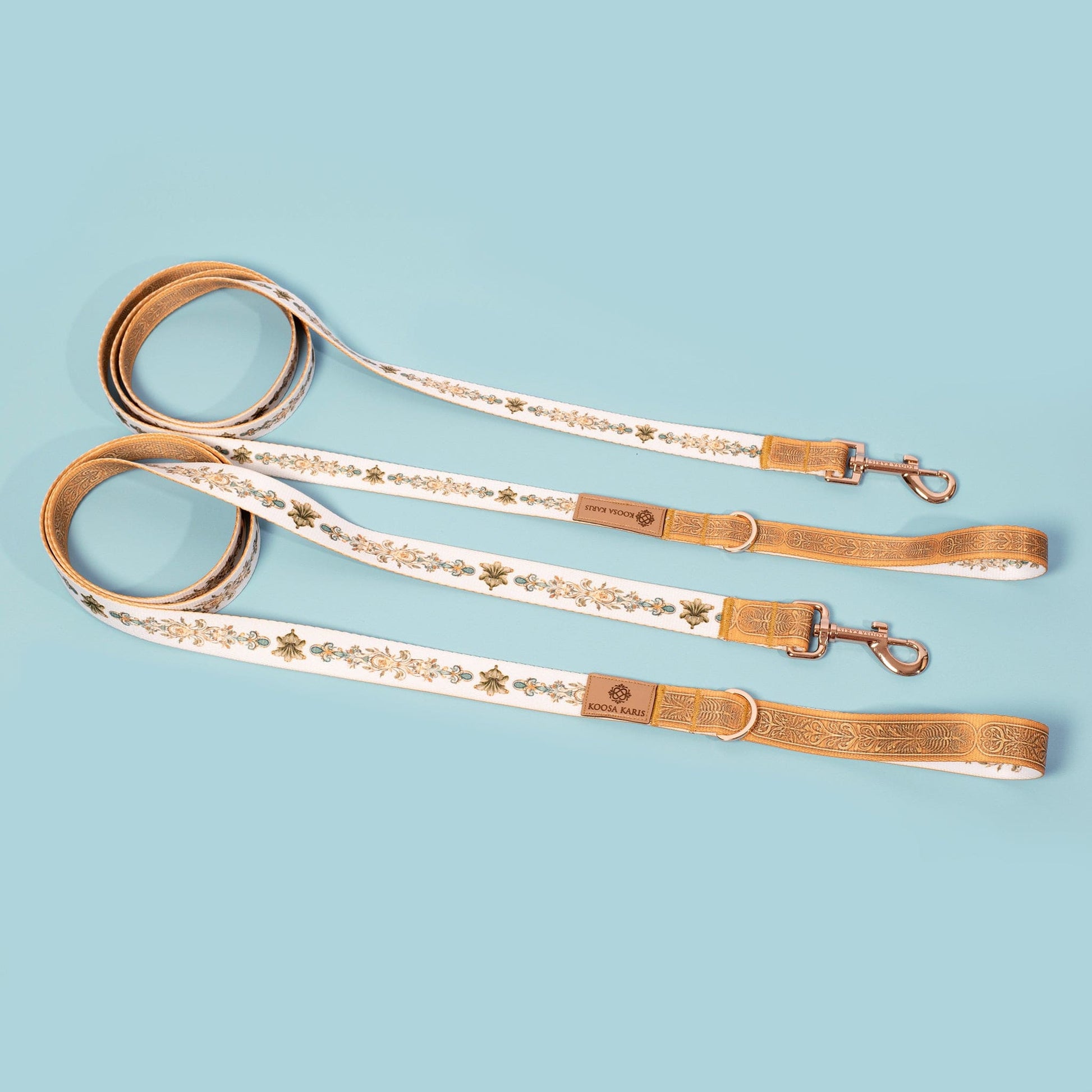 White and yellow dog leashes with  yellow, green and teal fancy scroll pattern and gold-toned hardware